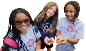 Three girls smile while holding coins.