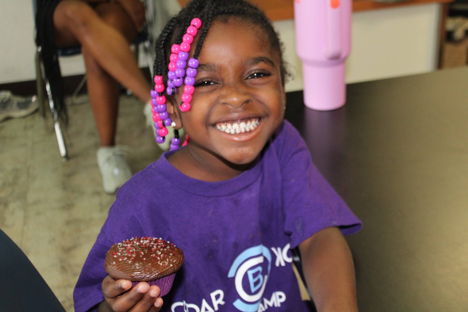 A young girl holding a chocolate doughnut in her hand.