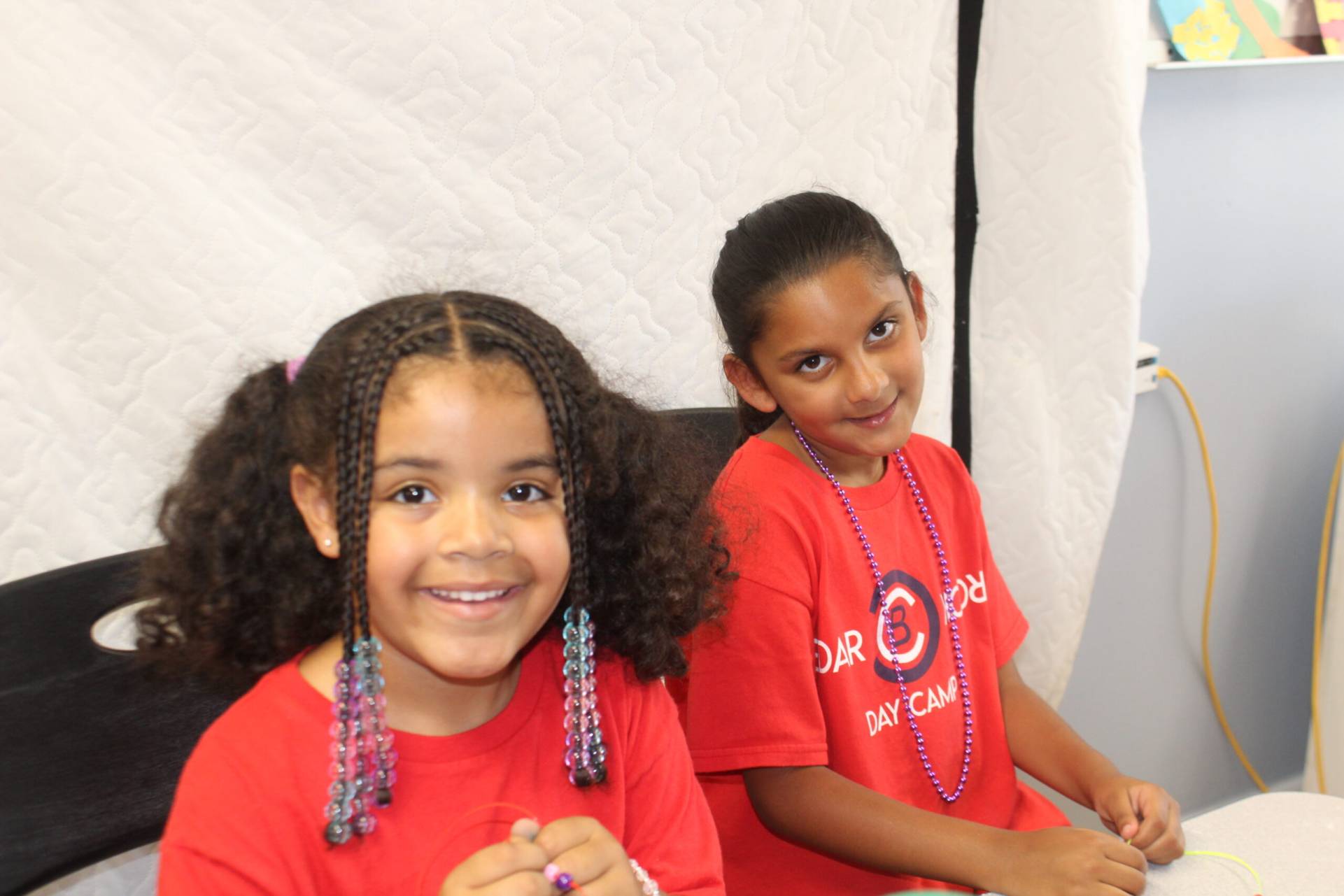 Two children sitting in a chair wearing red shirts.